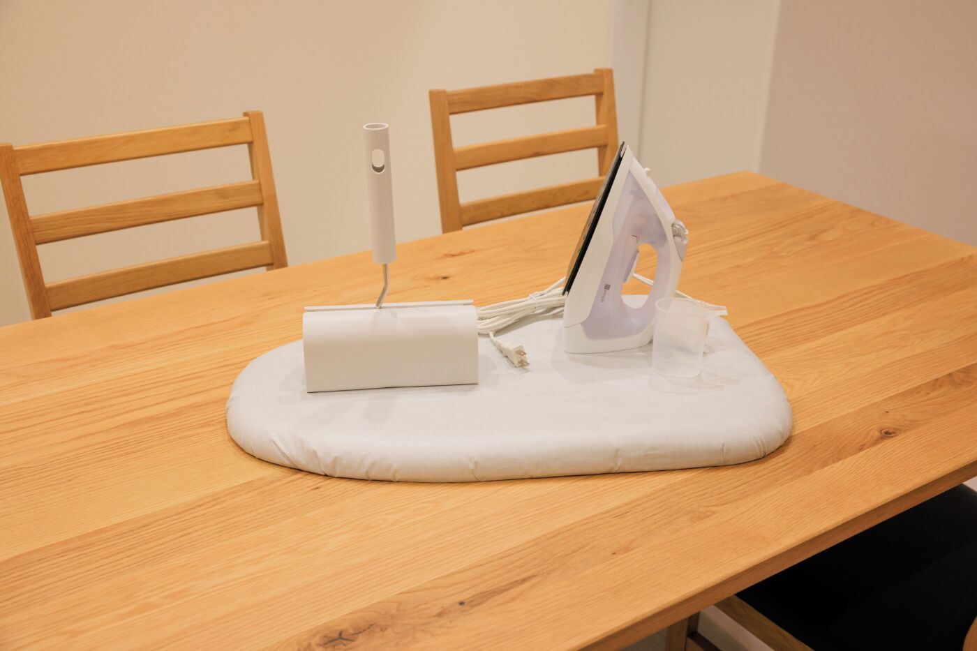 A wooden table with an ironing board, an iron, and a power strip.