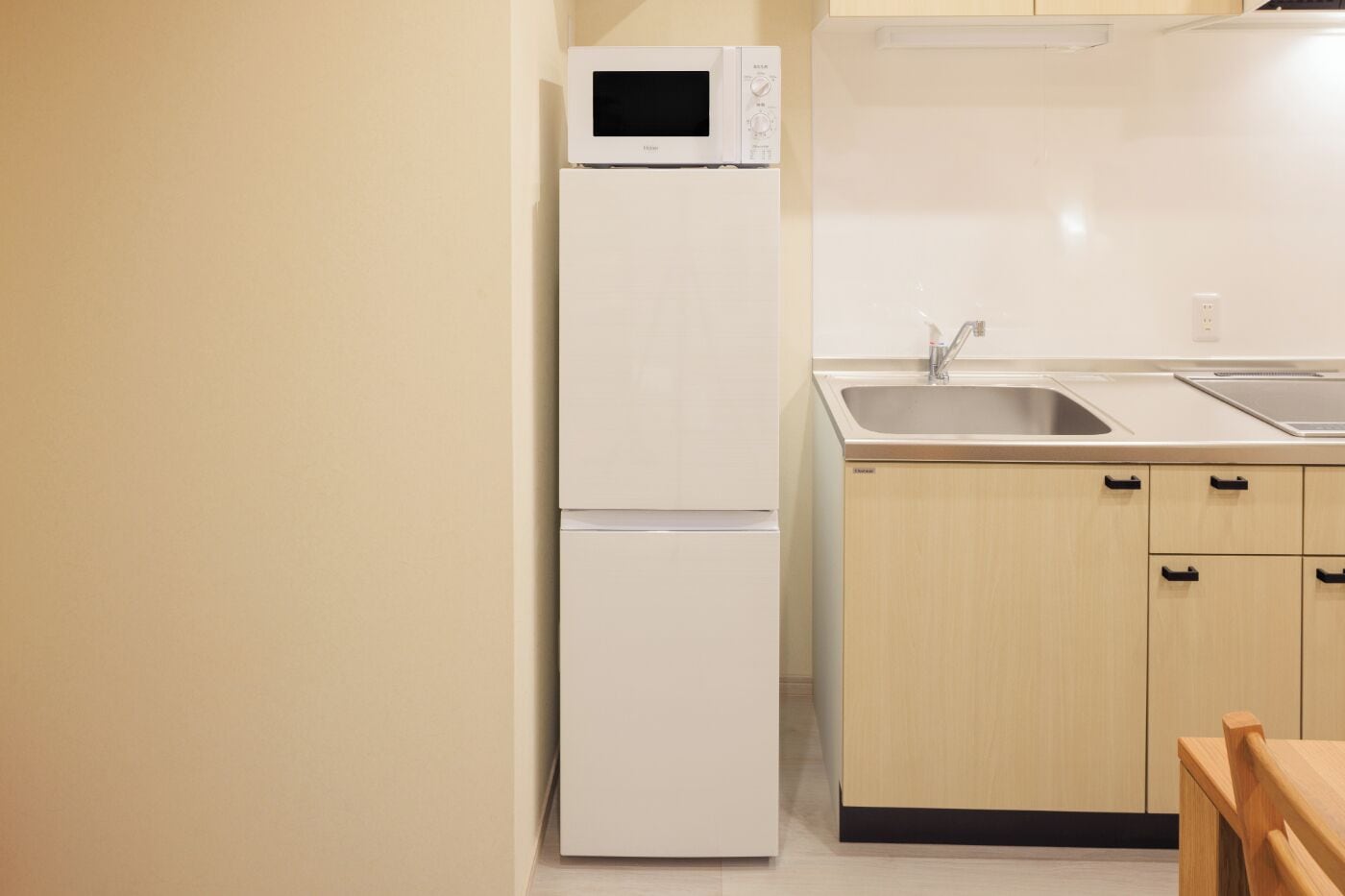 A compact kitchen with a white refrigerator, a microwave, a sink, and wooden cabinets.