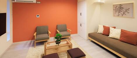 A modern living room with two armchairs, a sofa, a coffee table, and a small potted plant.