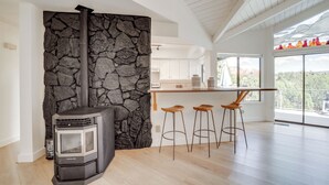 A modern kitchen with a stone wall, a wood-burning stove, and a bar area with stools. - Walk to Park & Trails! Mtn-view Sedona Haven (Sedona)
