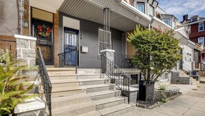 A townhouse with a stone facade, a front porch, and a staircase leading to the entrance. - Private Backyard Jawn! Multi-level Philly Rowhouse (Philadelphia)