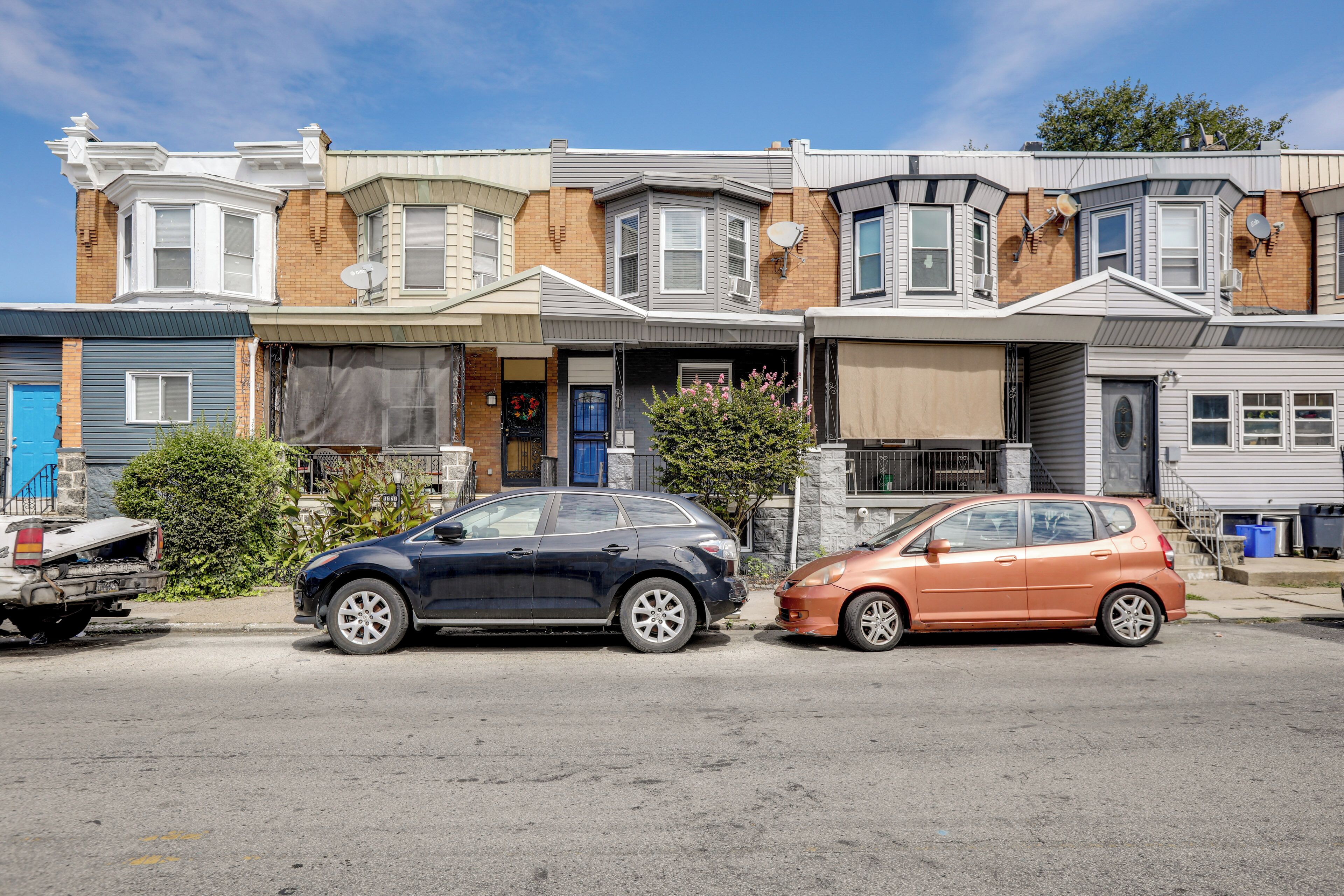 A row of townhouses with a garage, a blue door, and a small tree in front.