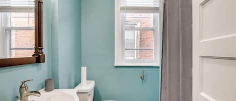 A bathroom with a white sink, toilet, and a window with blinds.