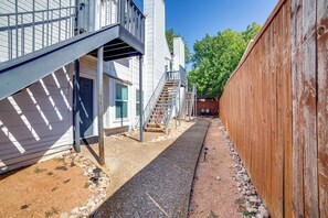 A residential property with a covered outdoor staircase, a gravel pathway, and a wooden fence.
