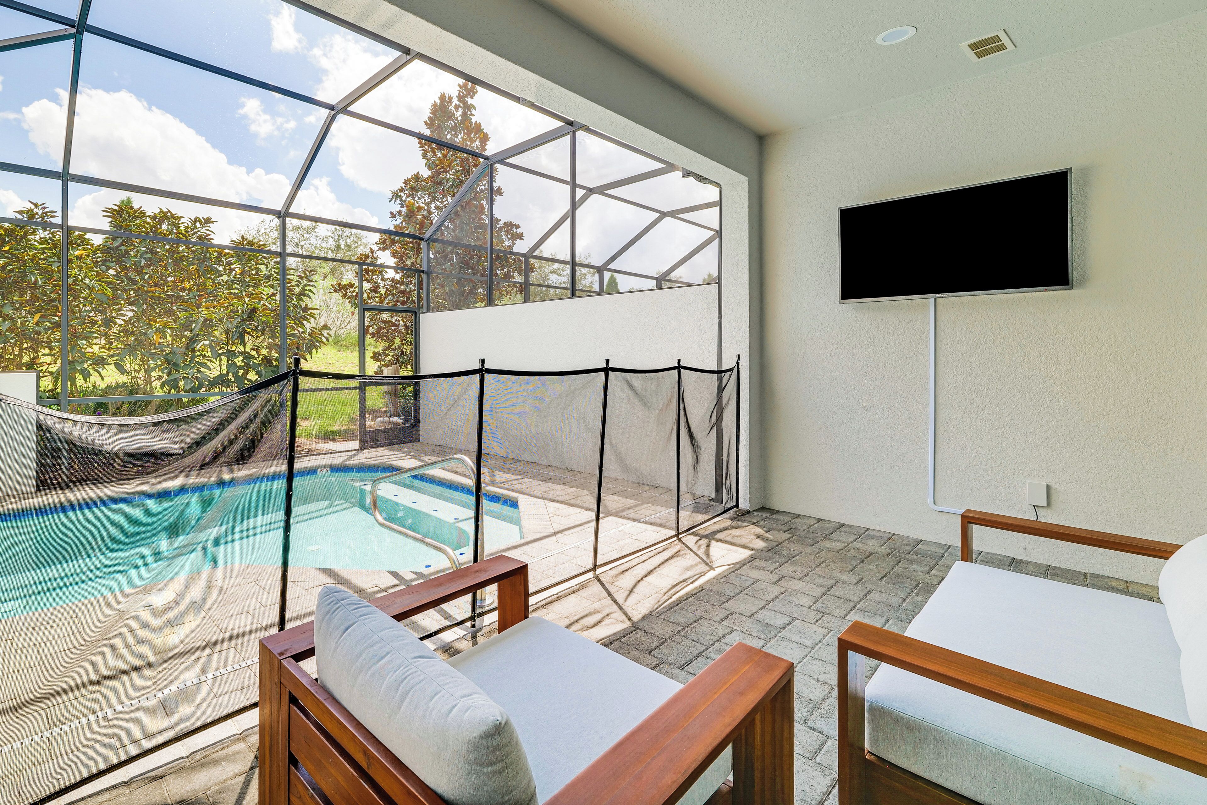 A modern room with a large window overlooking a swimming pool, a television mounted on the wall, and two wooden-framed beds.
