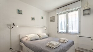 A bedroom with a bed, bedside table, window, and wall-mounted artwork. - Apartment "400m from the Beach" with Balcony (Fréjus)