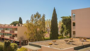 A rooftop terrace with outdoor seating, surrounded by buildings and trees. - Apartment "400m from the Beach" with Balcony (Fréjus)