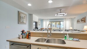 A kitchen with a double sink, white cabinets, and a view of the outside. - Direct Beach Access! Walkable Condo on Ocean Blvd (North Myrtle Beach)