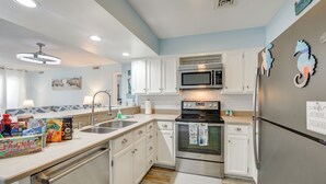 A kitchen with white cabinets, stainless steel appliances, and a tiled backsplash. - Direct Beach Access! Walkable Condo on Ocean Blvd (North Myrtle Beach)