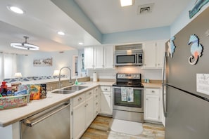 A kitchen with white cabinets, stainless steel appliances, and a tiled backsplash.