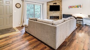 Un salon moderne avec un canapé d’angle, une cheminée, un téléviseur à écran plat et un plancher en bois franc.