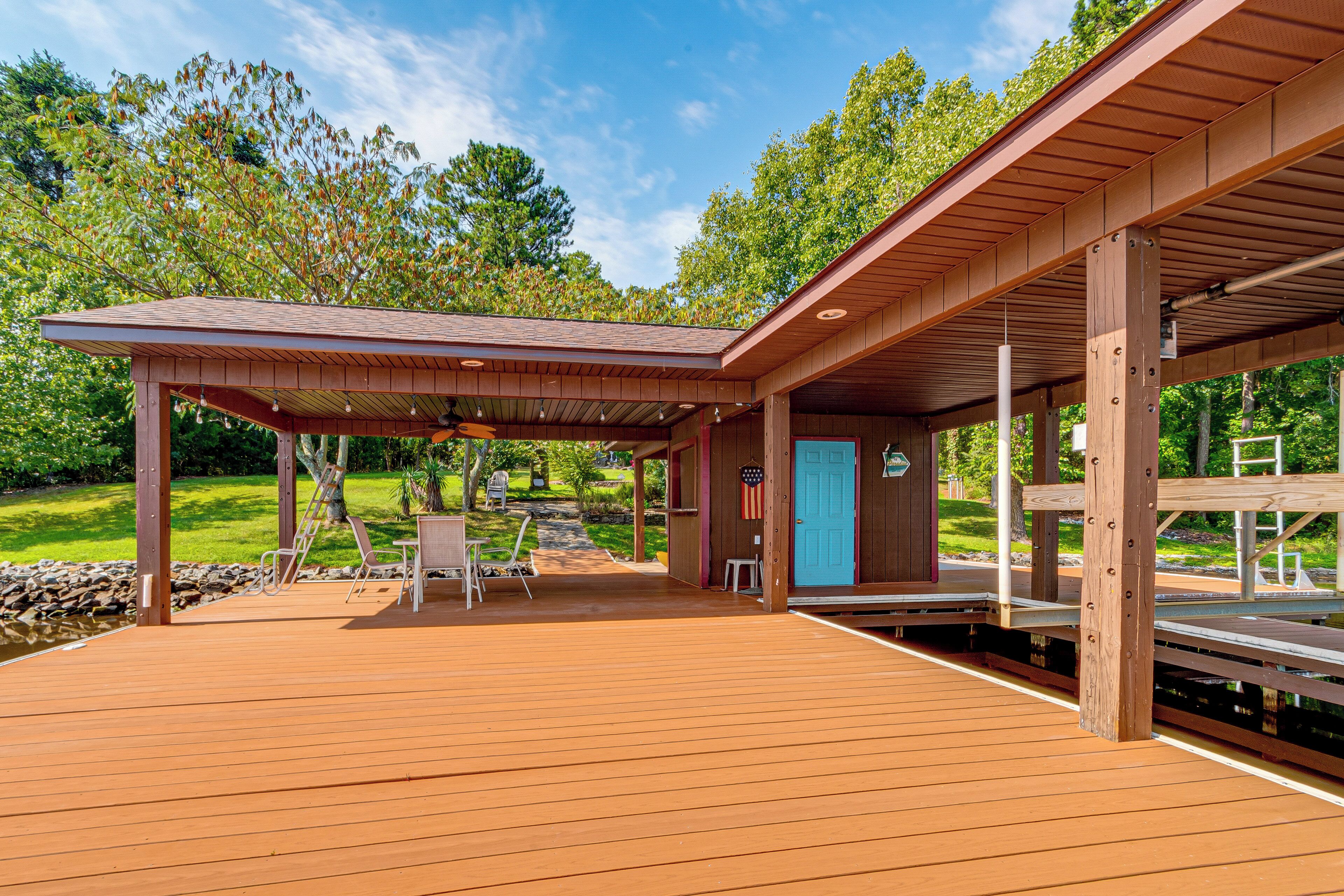 Une terrasse en bois avec un espace patio couvert, des sièges d’extérieur et une porte ornée d’un drapeau américain.