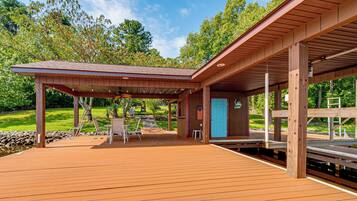 Une terrasse en bois avec un espace patio couvert, des sièges d’extérieur et une porte ornée d’un drapeau américain.