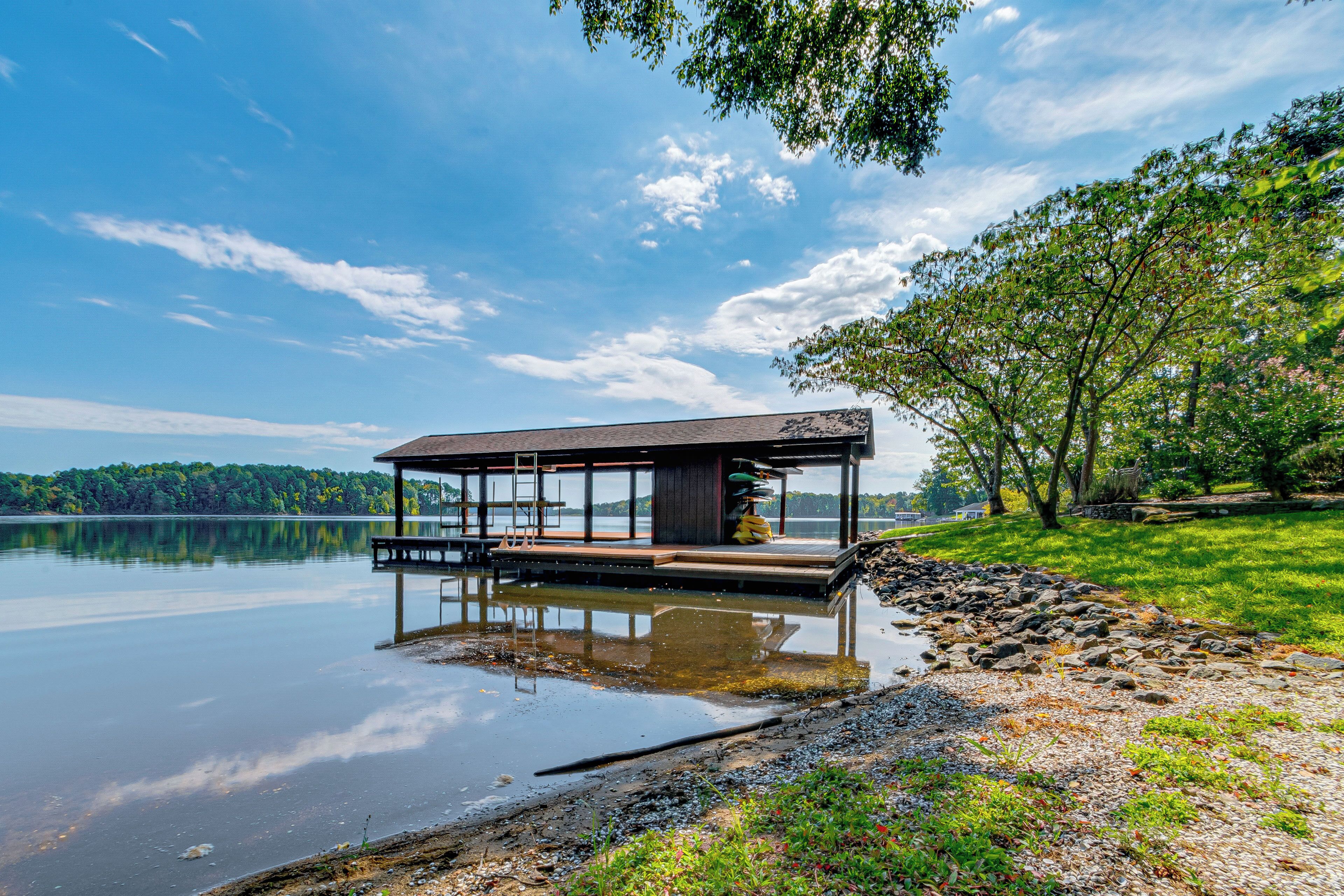 A lakeside cabin with a deck, surrounded by trees and a calm lake.