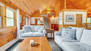 L’intérieur chaleureux d’un chalet avec des murs en bois, un escalier, un canapé et une table basse.