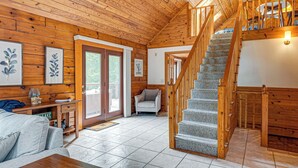 Un intérieur en bois avec un escalier, un canapé et une porte donnant sur l’extérieur.