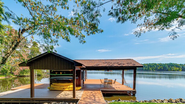 Une jetée en bois s’avançant dans un lac paisible, avec un espace de repos abrité et un petit pavillon.