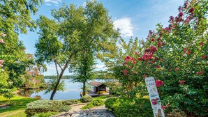 Une propriété au bord du lac, dotée d’un chemin en pierre, d’une végétation luxuriante et d’un panneau indiquant « The Lake Place ».