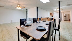 A spacious dining area with a long table set for six, a sofa, and a kitchen in the background. - Near Trails & Live Music: Cozy Atlanta Apt! (Atlanta)