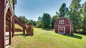 A barn with a wooden staircase leading up to a covered area, surrounded by a grassy field and trees. - Near Trails & Live Music: Cozy Atlanta Apt! (Atlanta)