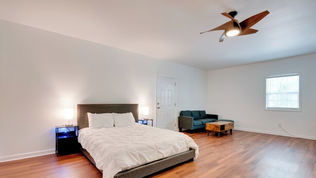 A bedroom with a bed, nightstands, a ceiling fan, a window, and a small table. - Near Trails & Live Music: Cozy Atlanta Apt! (Atlanta)