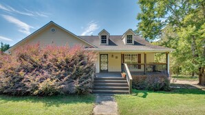 A two-story house with a front porch, a small garden, and a clear sky. - Unwind, Golf & Explore: Unique Atlanta Escape! (Atlanta)
