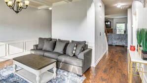 Ein modernes Wohnzimmer mit einem grauen Sofa, einem Holztisch und einer Chandelier.