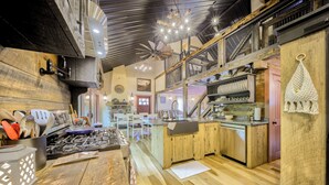 Une cuisine rustique avec des meubles en bois, une cuisinière à gaz et un luminaire suspendu.