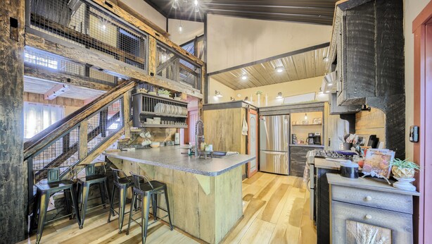 Une cuisine spacieuse dotée d’un îlot central, de planchers en bois et d’une mezzanine accessible par un escalier.