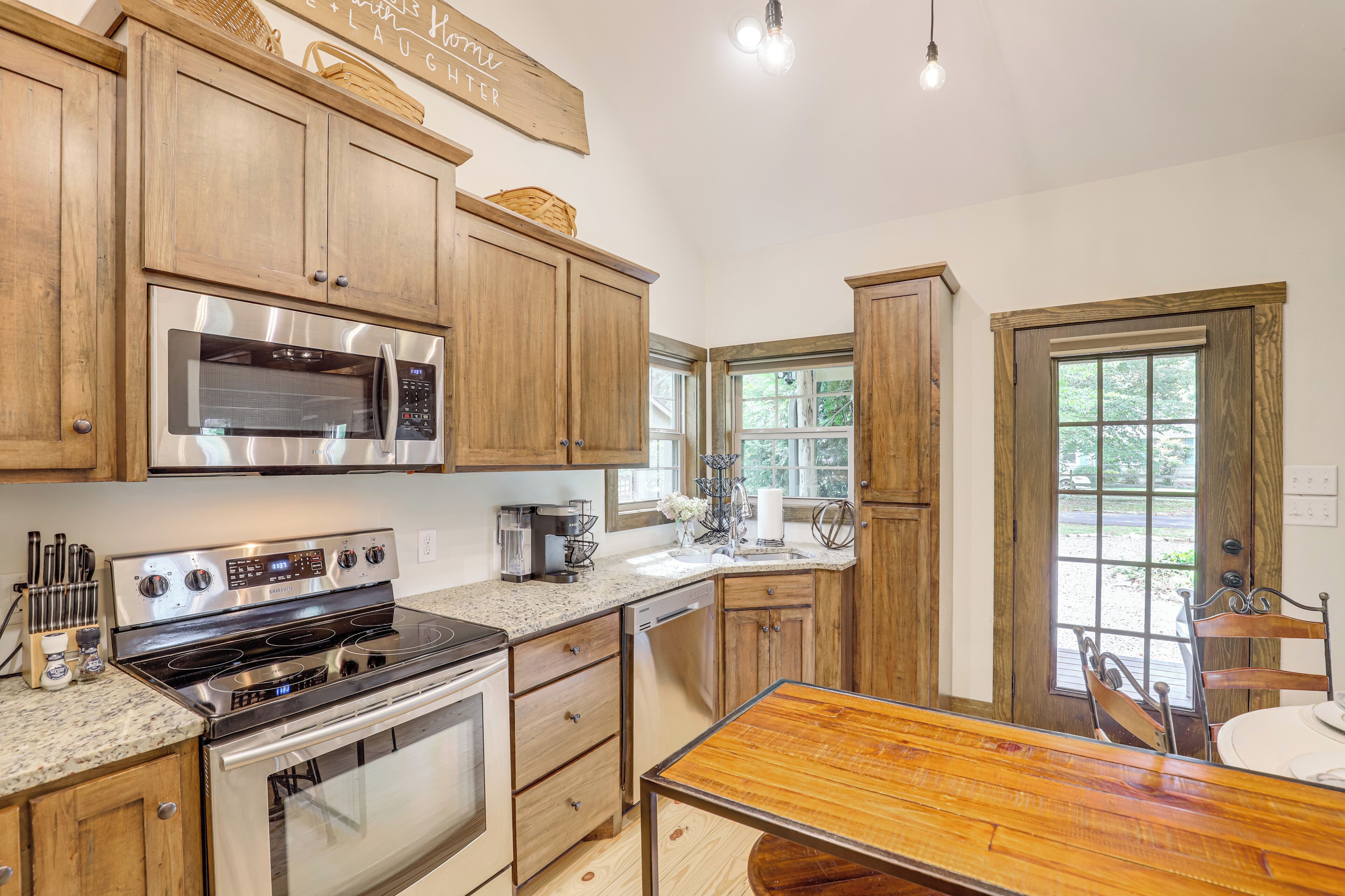 A kitchen with wooden cabinets, stainless steel appliances, a granite countertop, and a dining area with a wooden table and chairs.