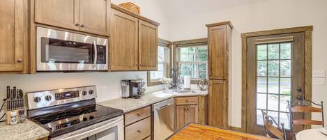 A kitchen with wooden cabinets, stainless steel appliances, a granite countertop, and a dining area with a wooden table and chairs.