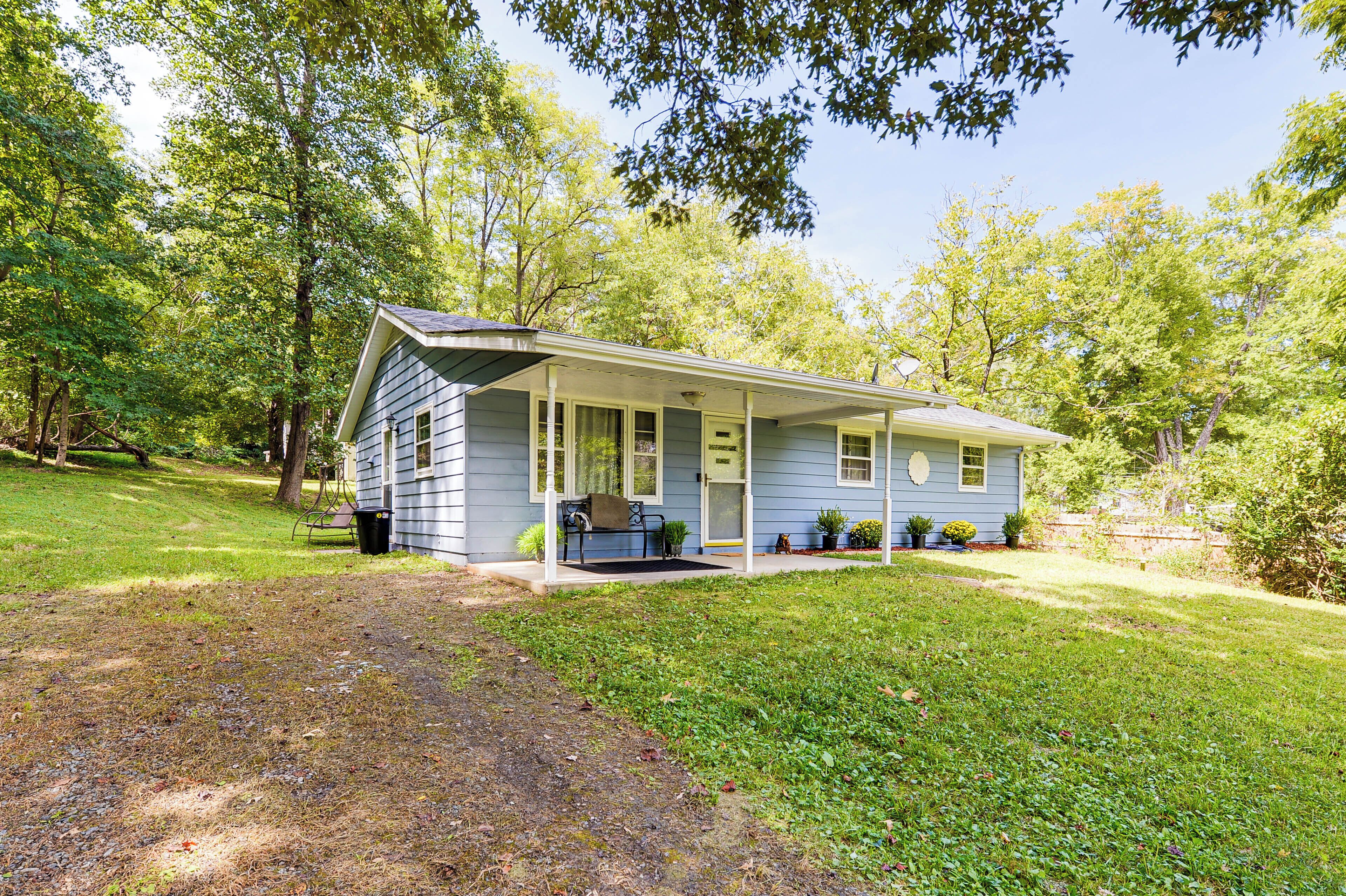 A single-story house with a porch, surrounded by a well-maintained lawn and trees.