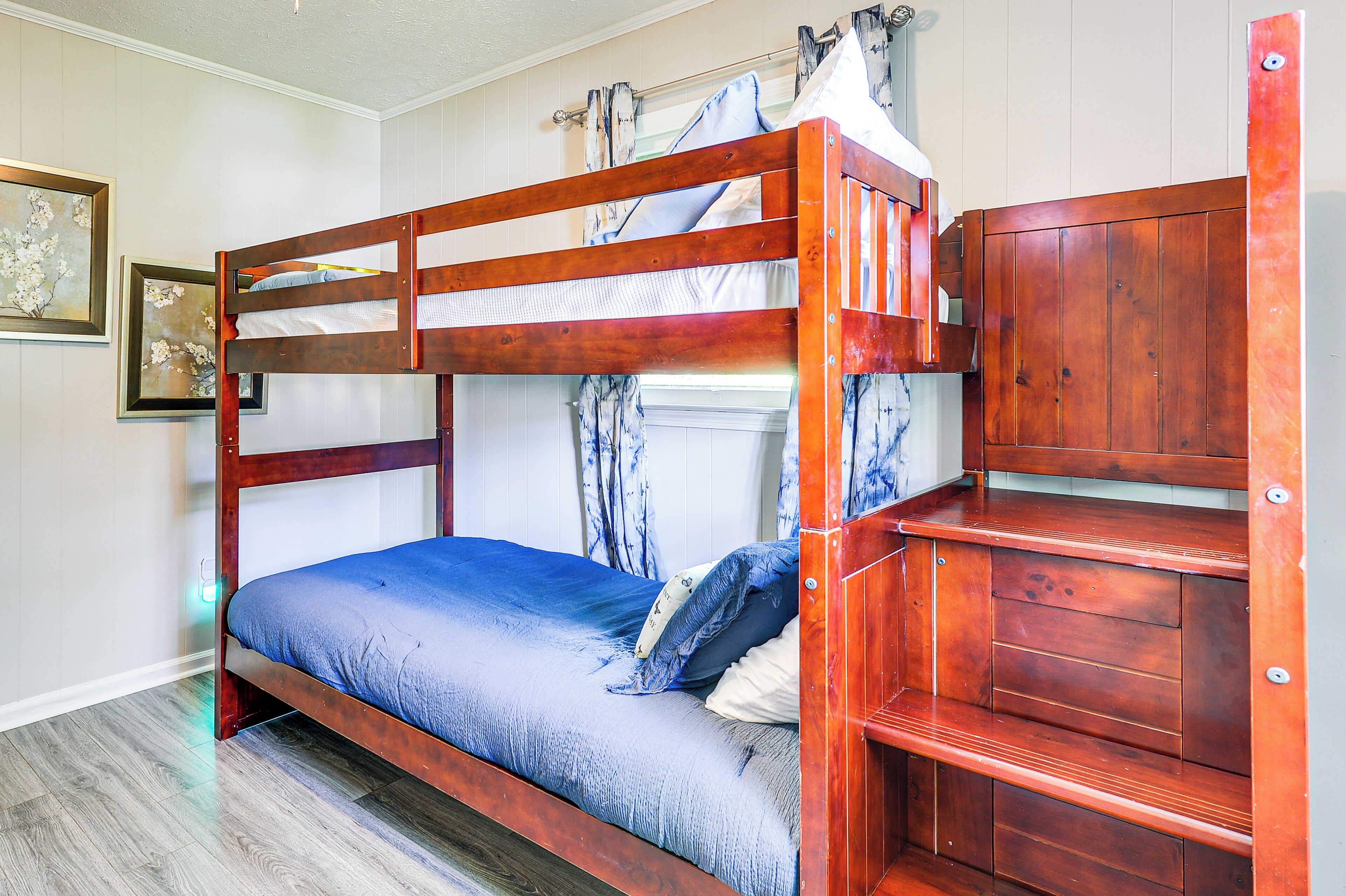 A bunk bed with a wooden frame and a lower bed with a blue mattress.