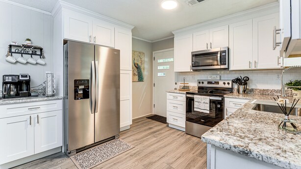 A modern kitchen with white cabinets, stainless steel appliances, and a granite countertop.