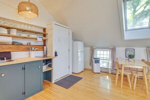 Une cuisine compacte avec des meubles en bois, un four encastré et un coin repas comprenant une table et des chaises.