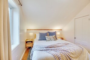 Une chambre à coucher avec un lit, des lampes de chevet, une table de chevet, une fenêtre et une porte.
