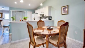 A dining area with a wooden table and chairs, a kitchen in the background, and a light blue wall. - Golf Course Community Home Near Springs & Swimming (Alachua)