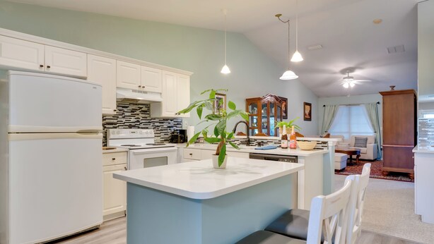 A modern kitchen with white cabinets, a central island, and pendant lighting. - Golf Course Community Home Near Springs & Swimming (Alachua)