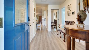A hallway with a blue door, wooden flooring, and a dining area with a wooden table and chairs. - Golf Course Community Home Near Springs & Swimming (Alachua)