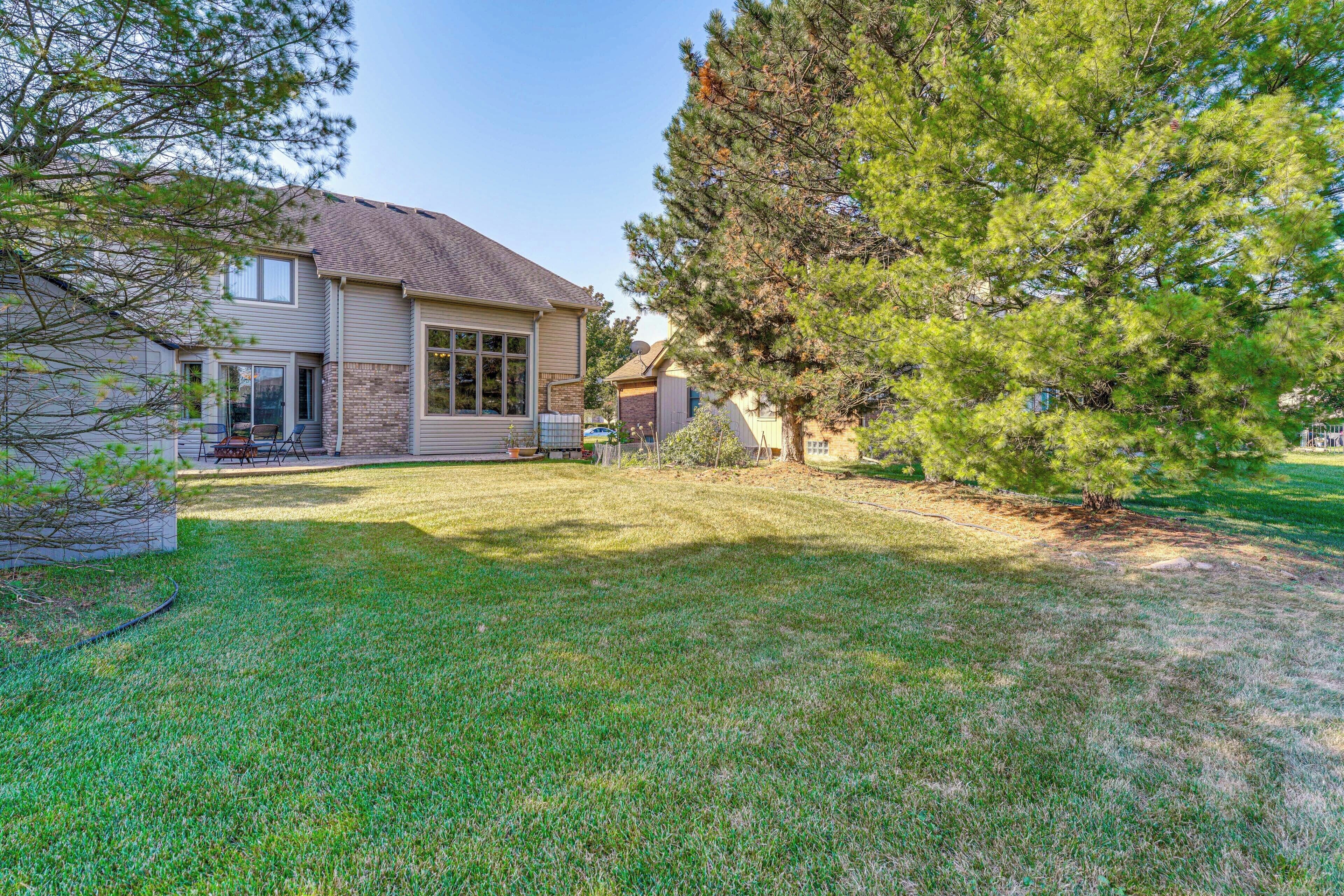 A two-story house with a well-maintained lawn and a large pine tree.