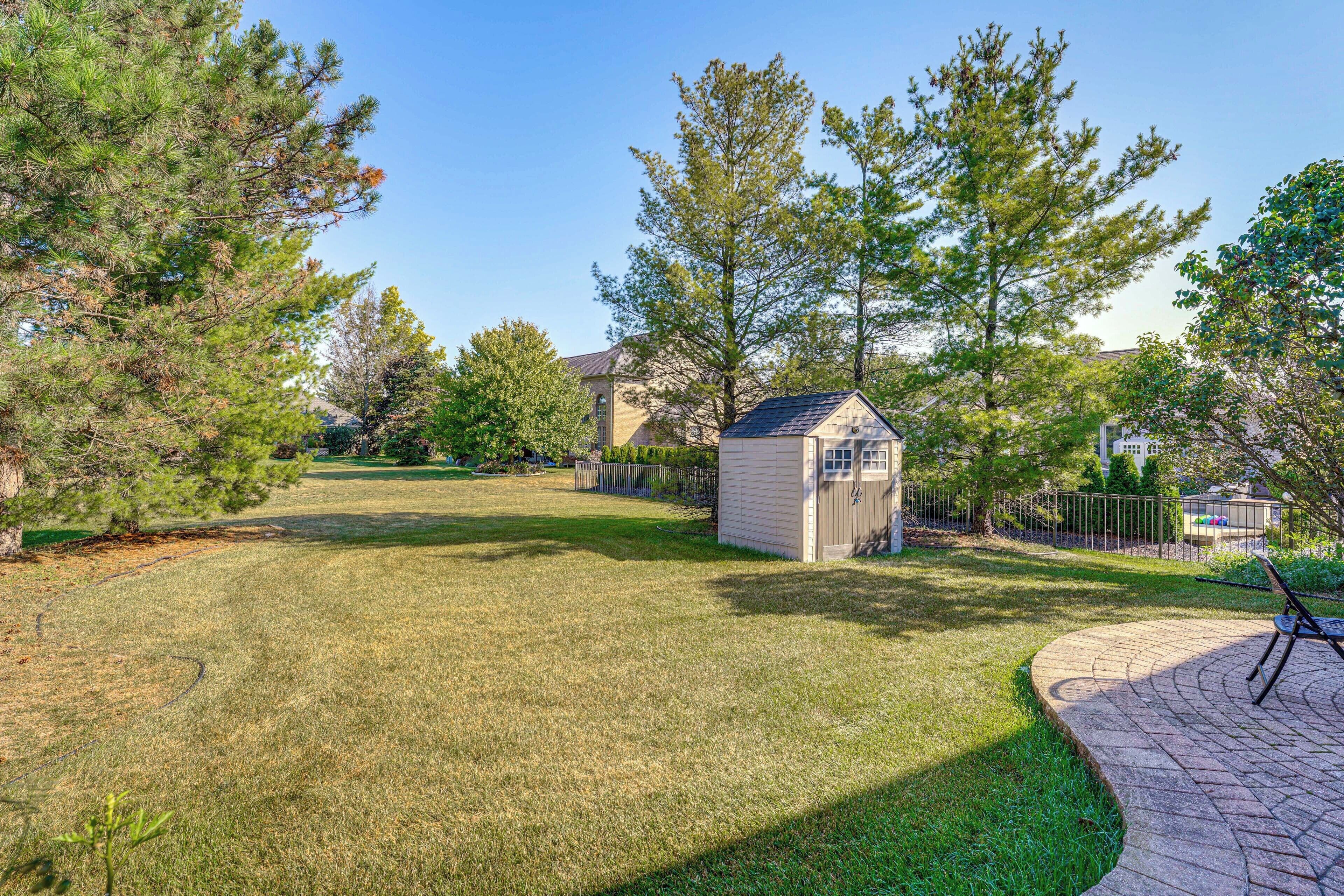 A well-maintained backyard with a small shed, a paved patio, and a lawn.