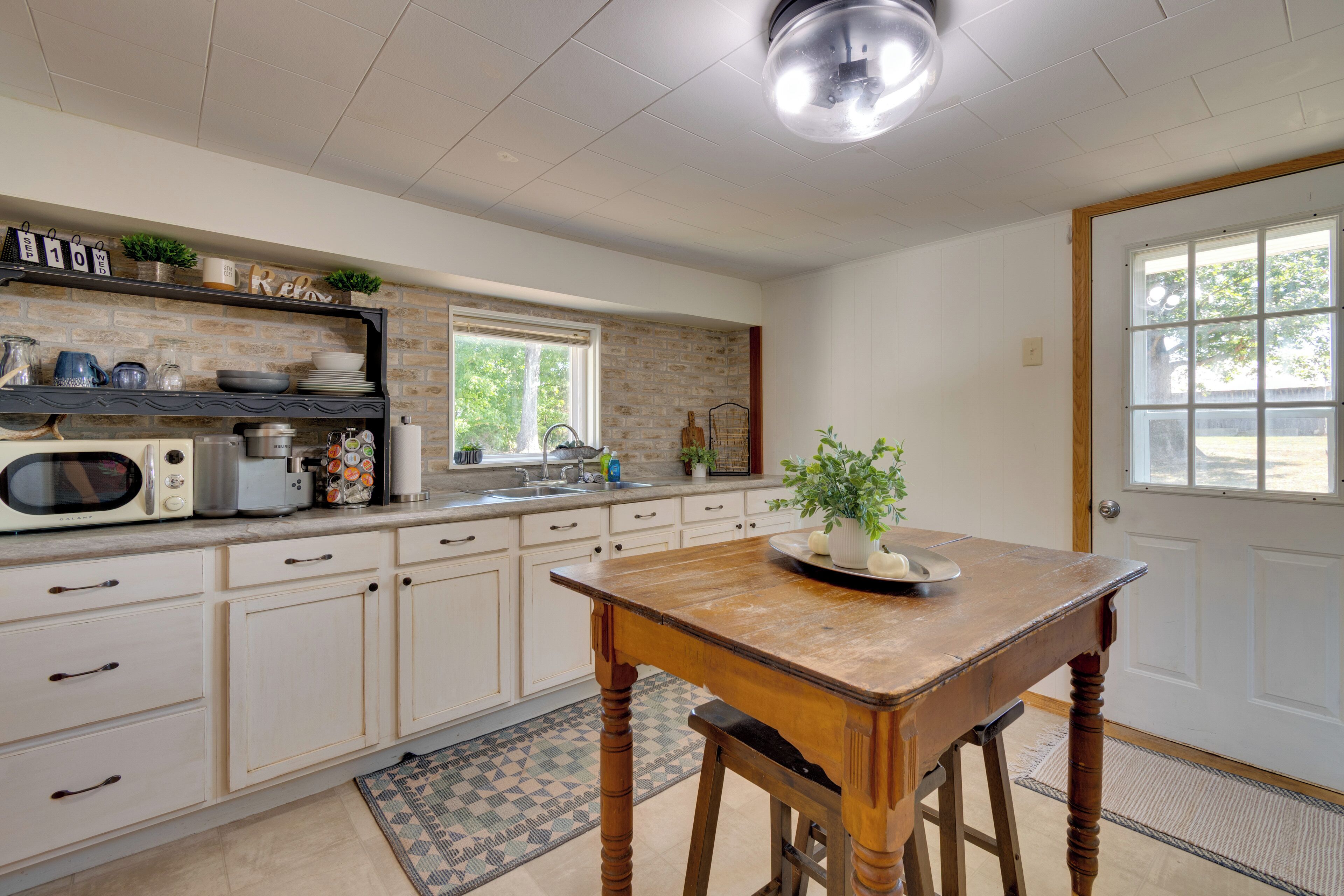 A kitchen with white cabinets, a wooden table, and a window.