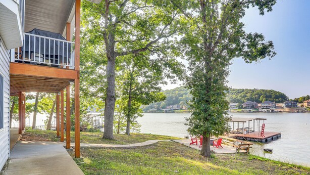 A lakeside property with a covered deck, a dock, and a grassy area. - Water-view Deck! Family Home on Lake of the Ozarks (Roach)