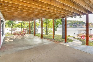 Un patio techado con piso de concreto, vigas de madera y sillas rojas.