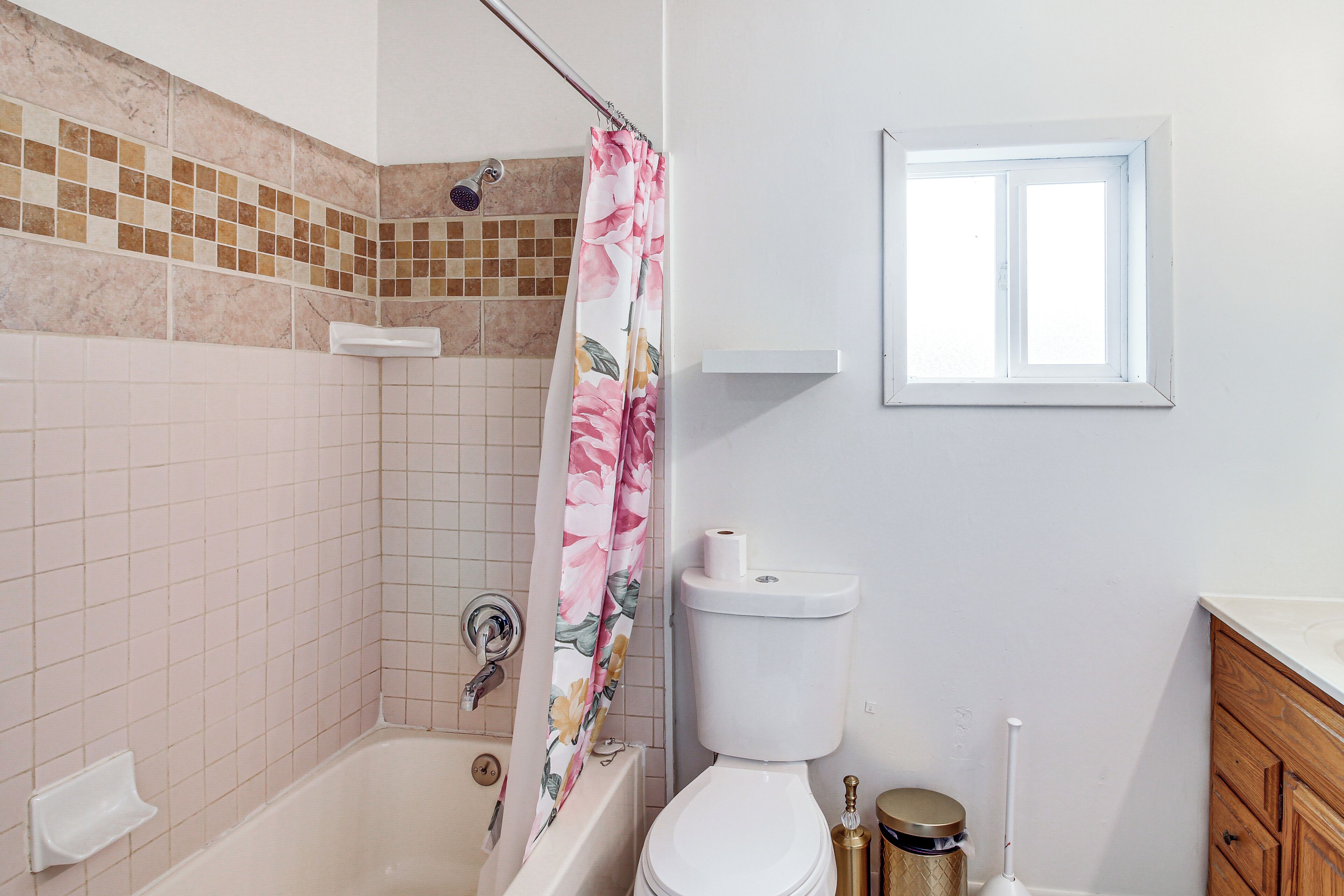 Une salle de bain avec une douche, des toilettes et une fenêtre.