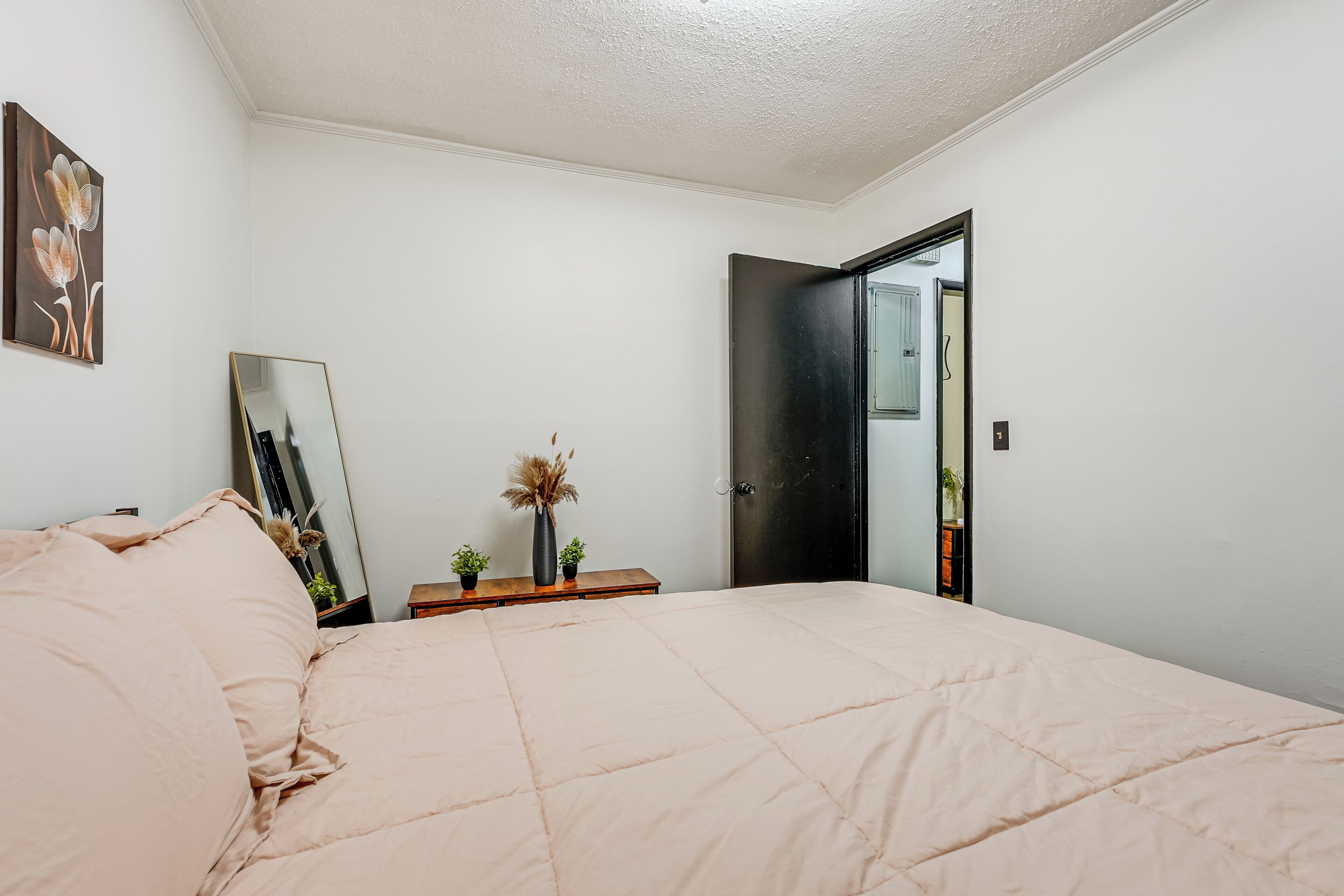A bedroom with a bed, a dresser, a mirror, and a door.