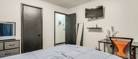 A bedroom with a bed, a desk, a chair, a TV, and a wardrobe.