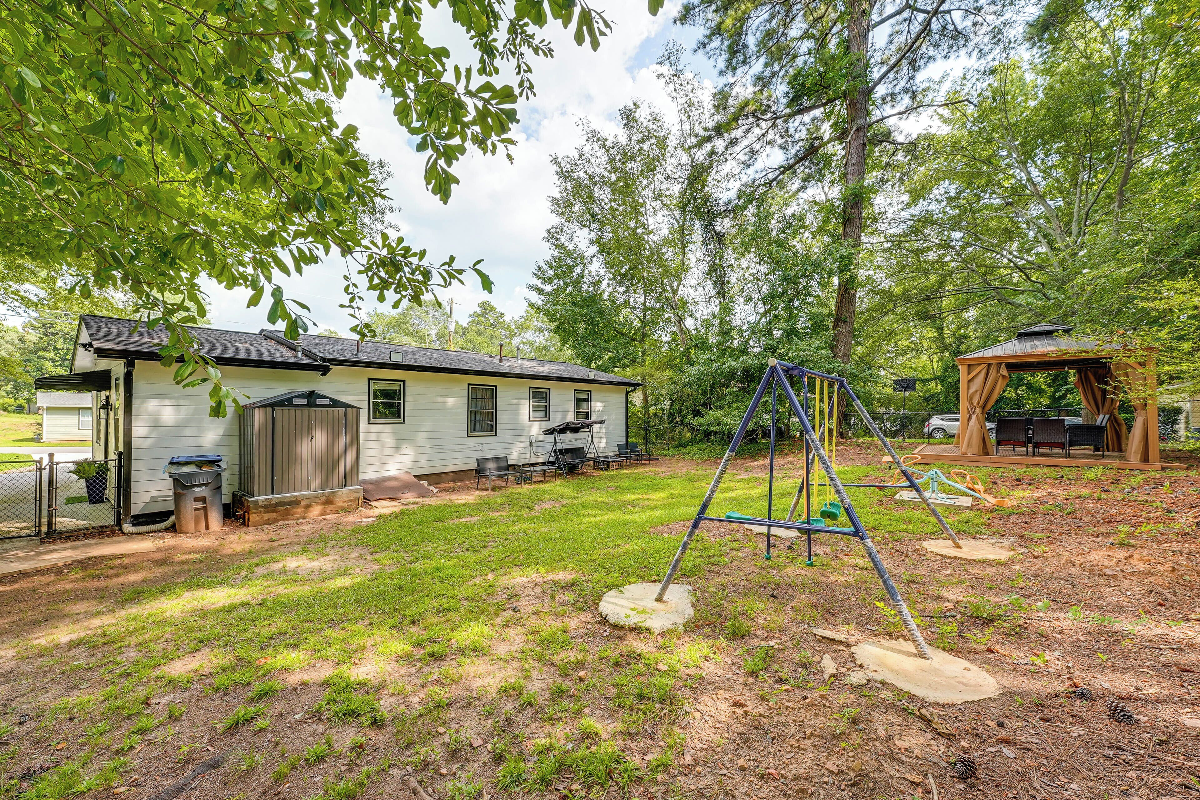 A residential property with a house, a swing set, and a covered play area.
