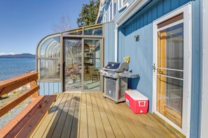 A deck with a grill, a cooler, and a glass enclosure overlooking a body of water. - 9 Mi to Mendenhall Glacier: Waterfront Juneau Home (Juneau)