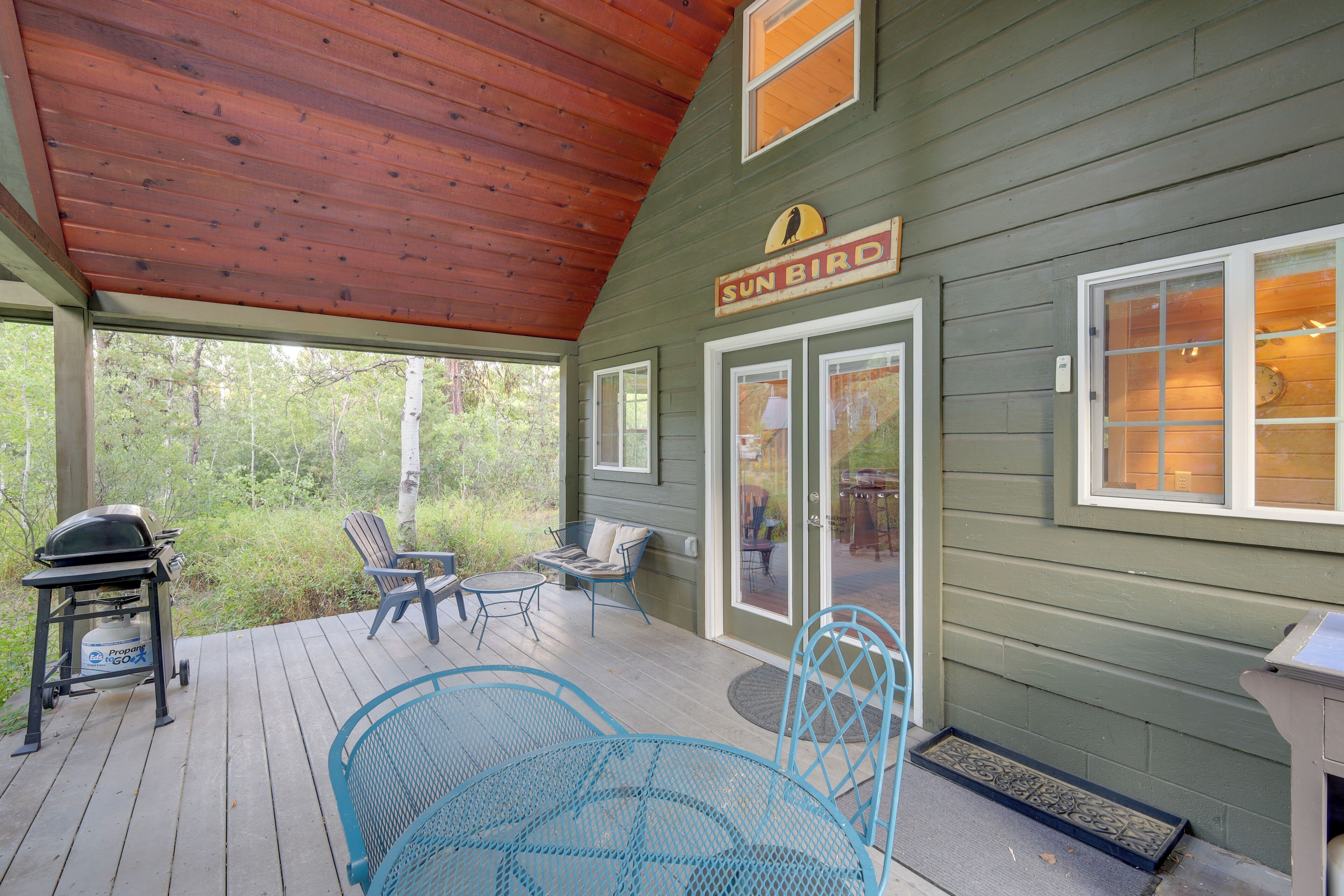 A covered deck with outdoor furniture, a grill, and a sign reading "SUN BIRD".